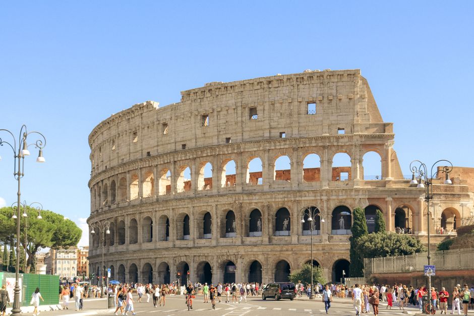 Roman Colosseum with tourists on a sunny summer day, showcasing its architectural grandeur.