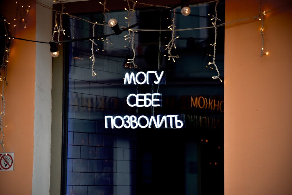Neon sign in Russian with decorative string lights at night.