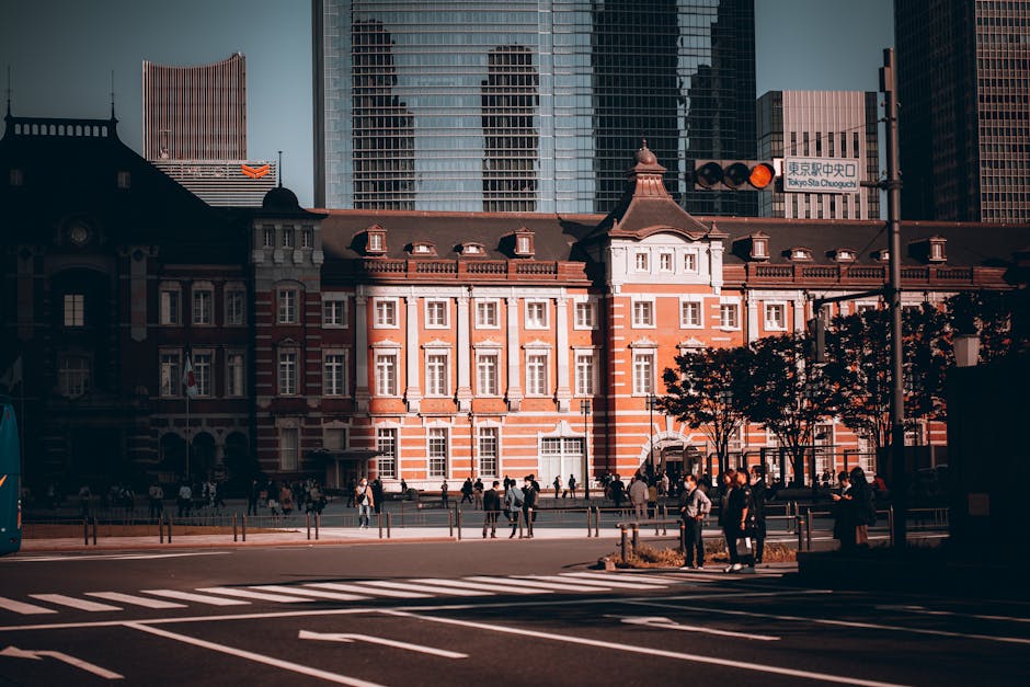 Capture of the historic Tokyo Station building with crowds on a sunlit street in Tokyo, Japan.