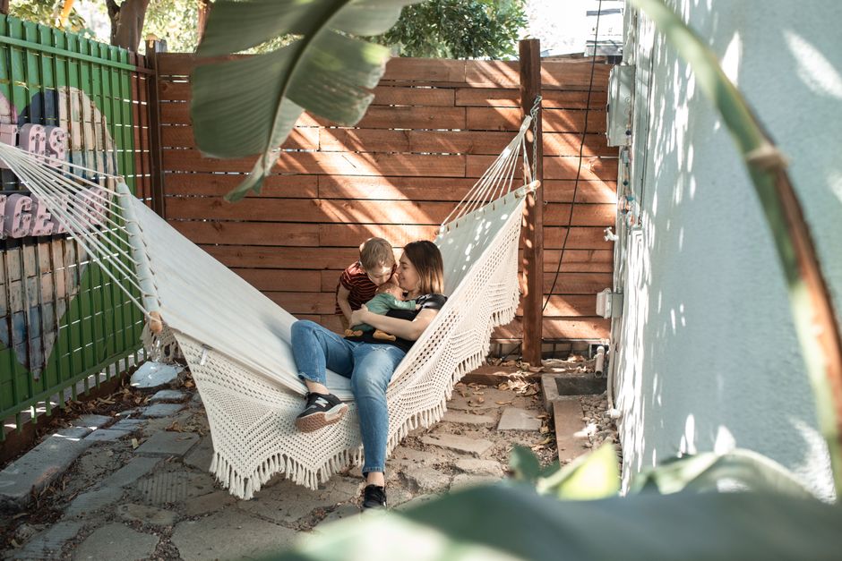 A mother and young son enjoy a peaceful moment together in a backyard hammock.