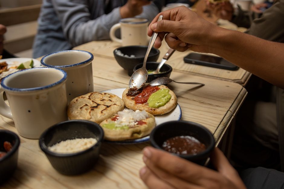 Close-up of friends enjoying traditional flatbreads with toppings at a cozy table.