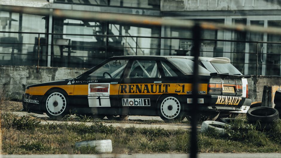 Classic Renault race car parked outdoors in an industrial location, showcasing retro motorsport design.
