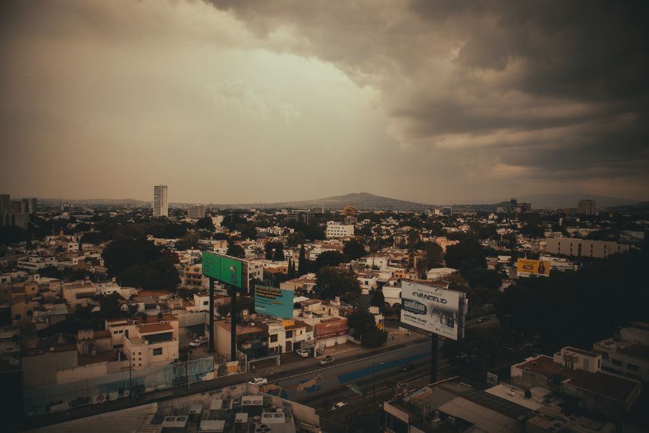 Aerial view of a cityscape with dark stormy clouds looming overhead, creating a dramatic urban atmosphere.