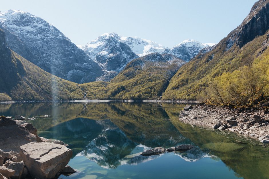 Breathtaking view of a calm lake reflecting snow-capped mountains in Norway.