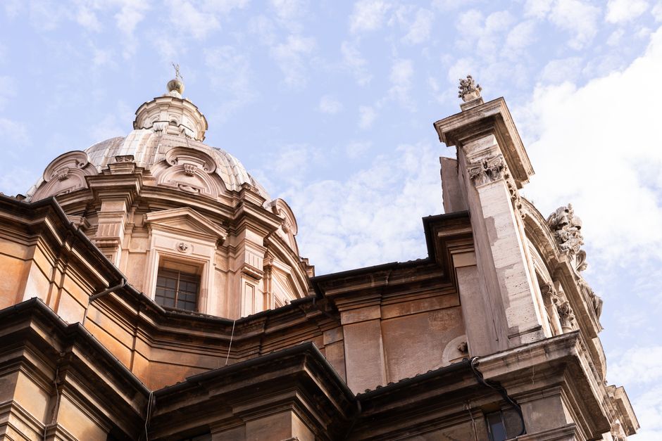 Close-up of a Baroque dome showcasing Roman architectural elegance against a blue sky.