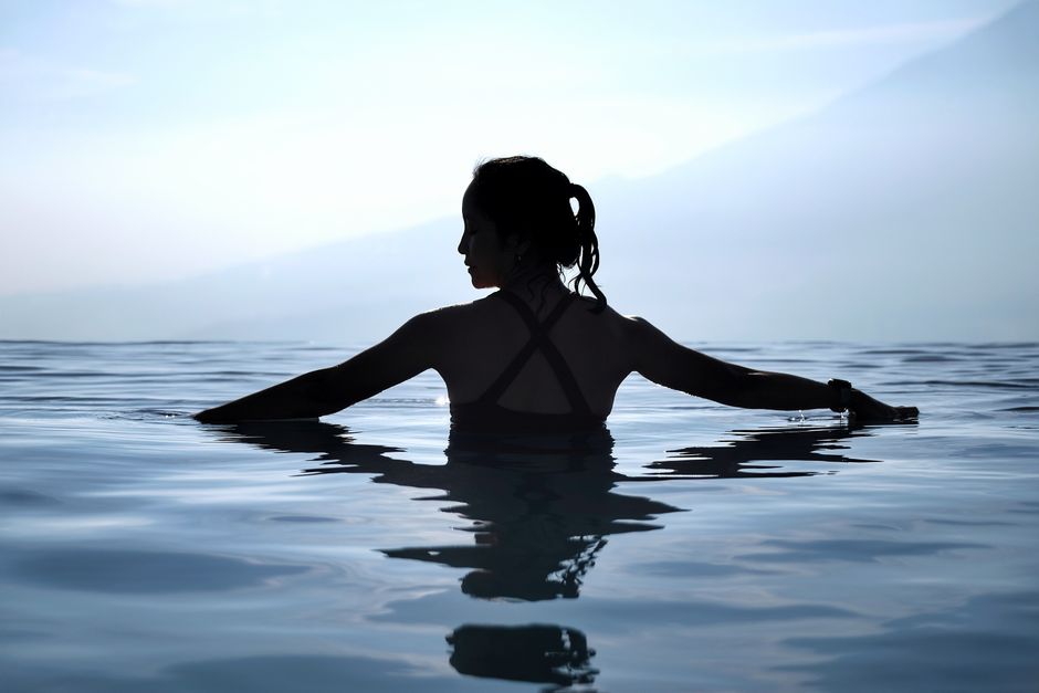 Serene silhouette of a woman enjoying an infinity pool at sunset in Jawa Barat, Indonesia.