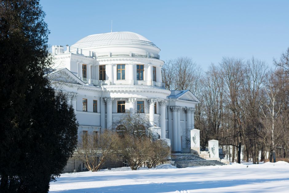 Snow-covered Yelagin Palace amidst wintery landscape in St. Petersburg.