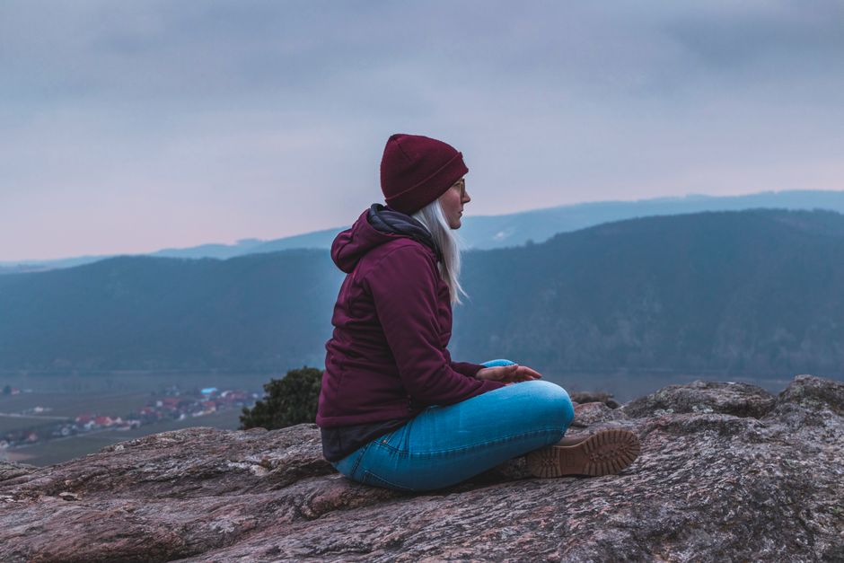 Woman sitting on a rock, enjoying the serene mountain view.