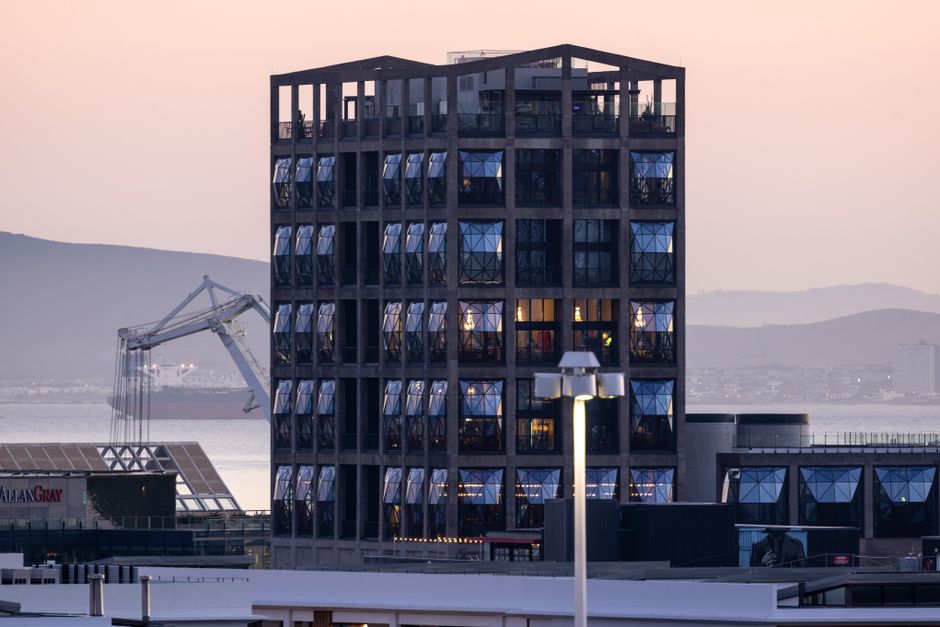 A contemporary building with reflective windows near Cape Town harbor during a serene sunset.