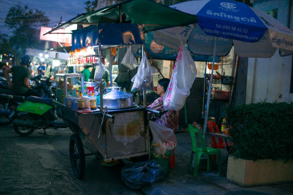 Street vendor at night in Golog, Qinghai, selling food under colorful umbrellas.