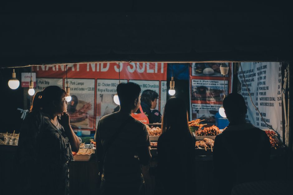 A vibrant night street food market in Cebu City with people enjoying Asian cuisine.