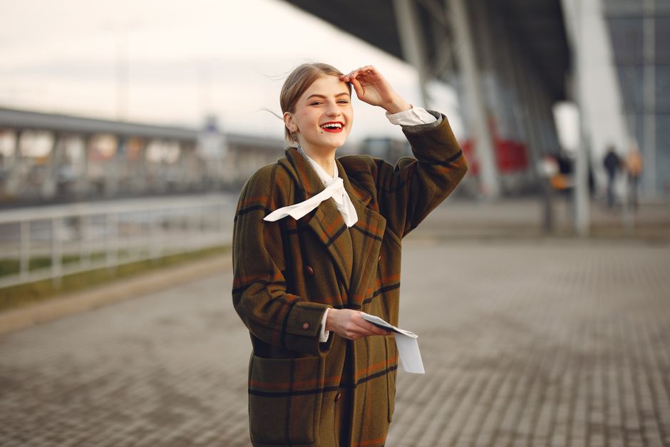 A happy woman in a plaid coat smiling outdoors, exuding warmth and style.